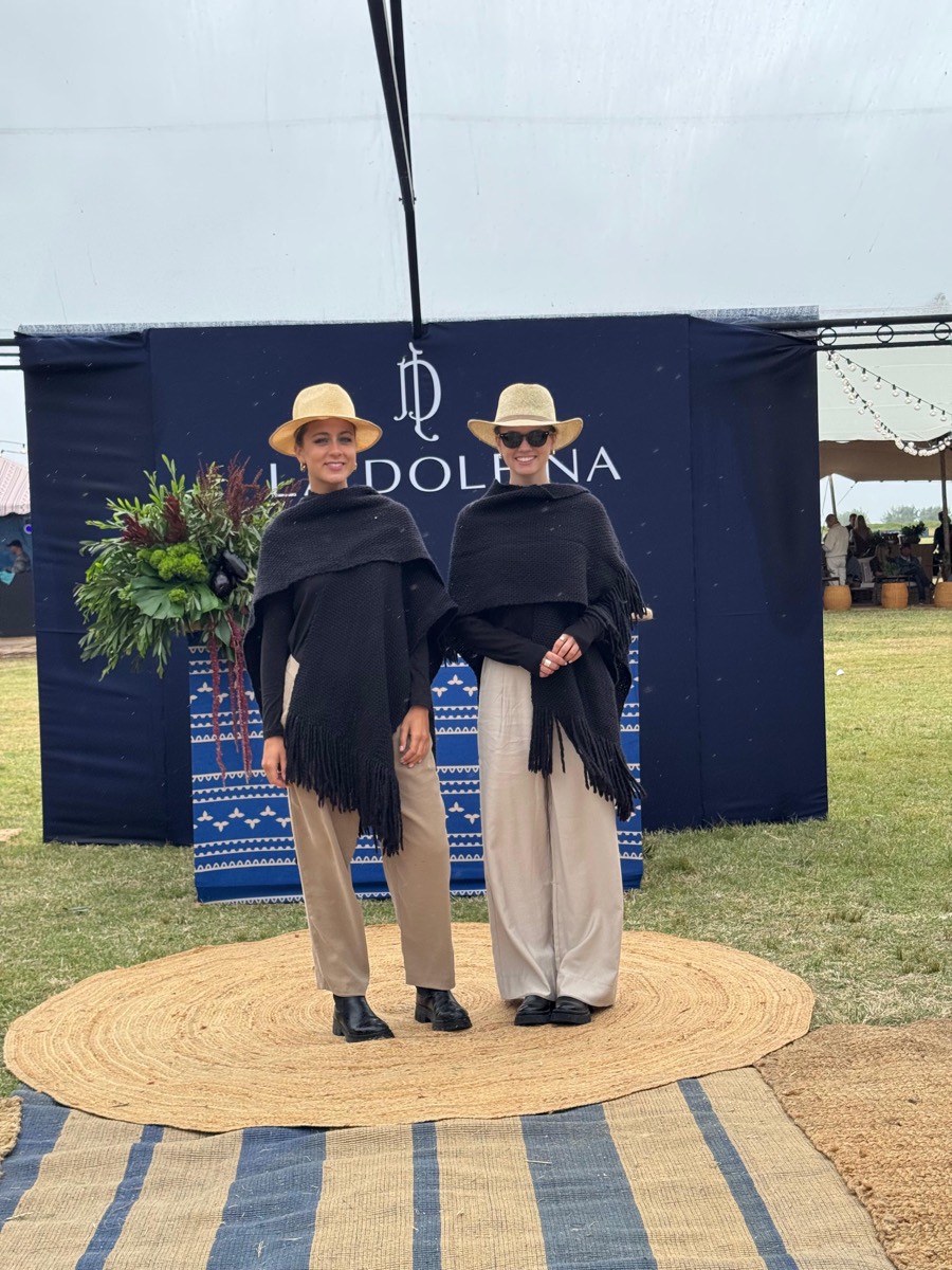Dos promotoras con poncho y sombrero frente al stand de La Dolfina.