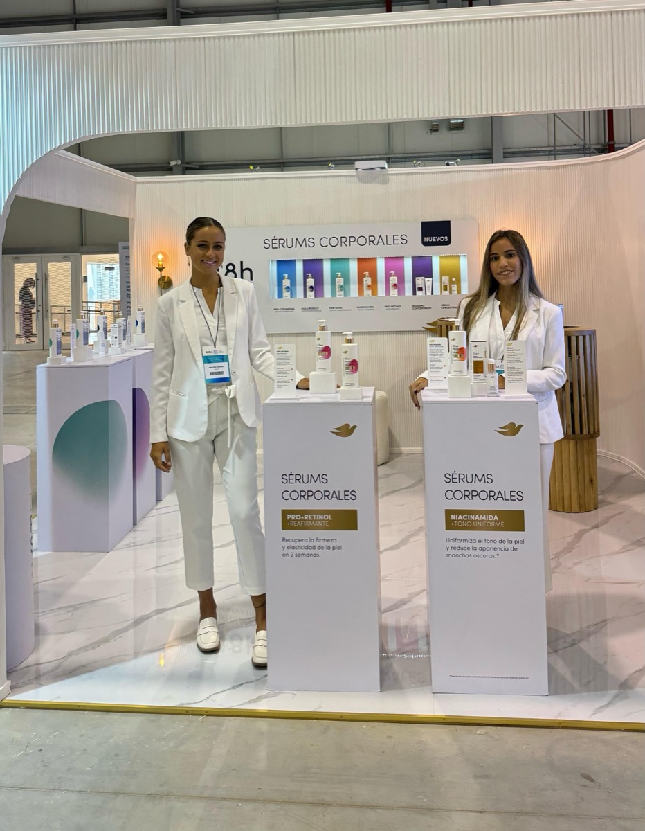 Dos promotoras de blanco en un stand de productos Dove.