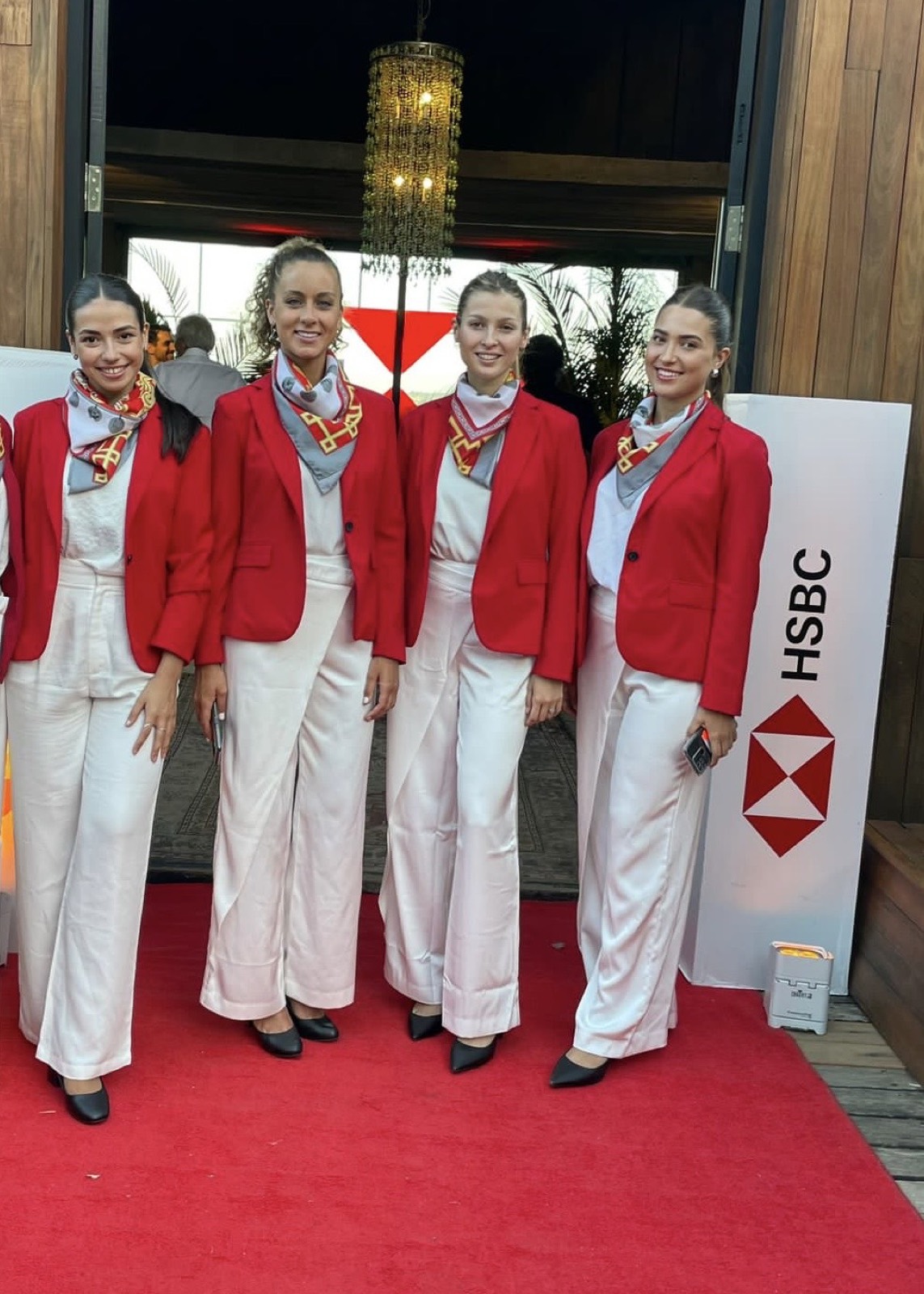Azafatas de rojo y blanco frente al backdrop de HSBC.
