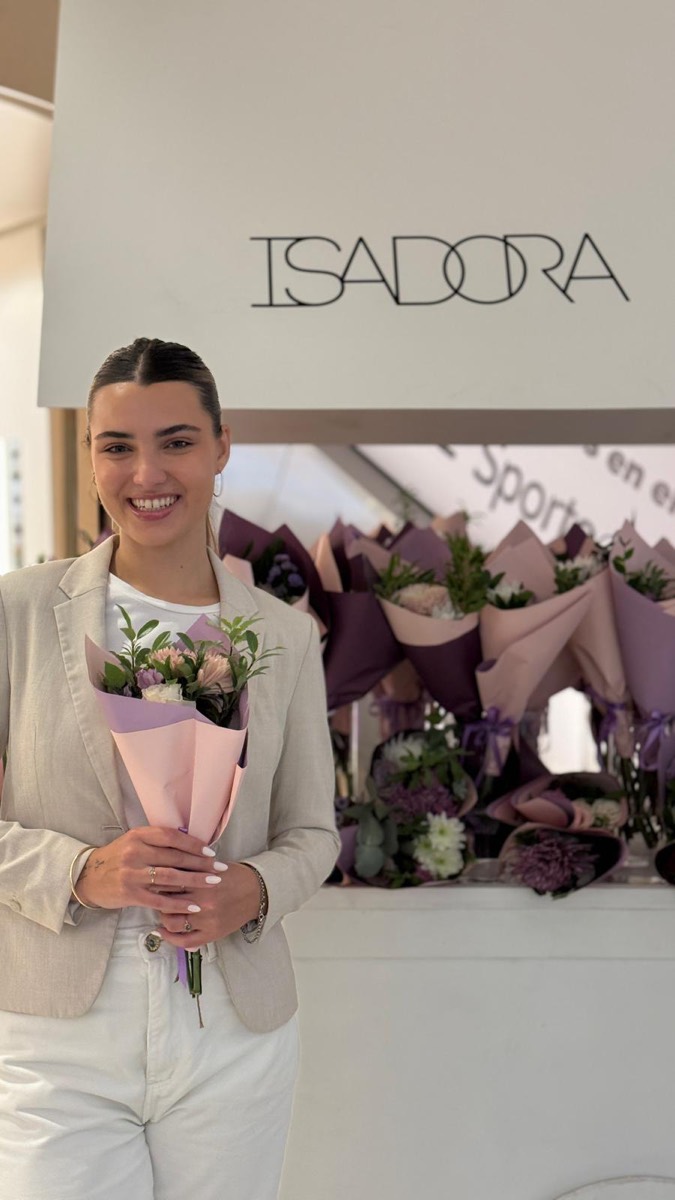 Promotora con un ramo de flores en el stand de Isadora.