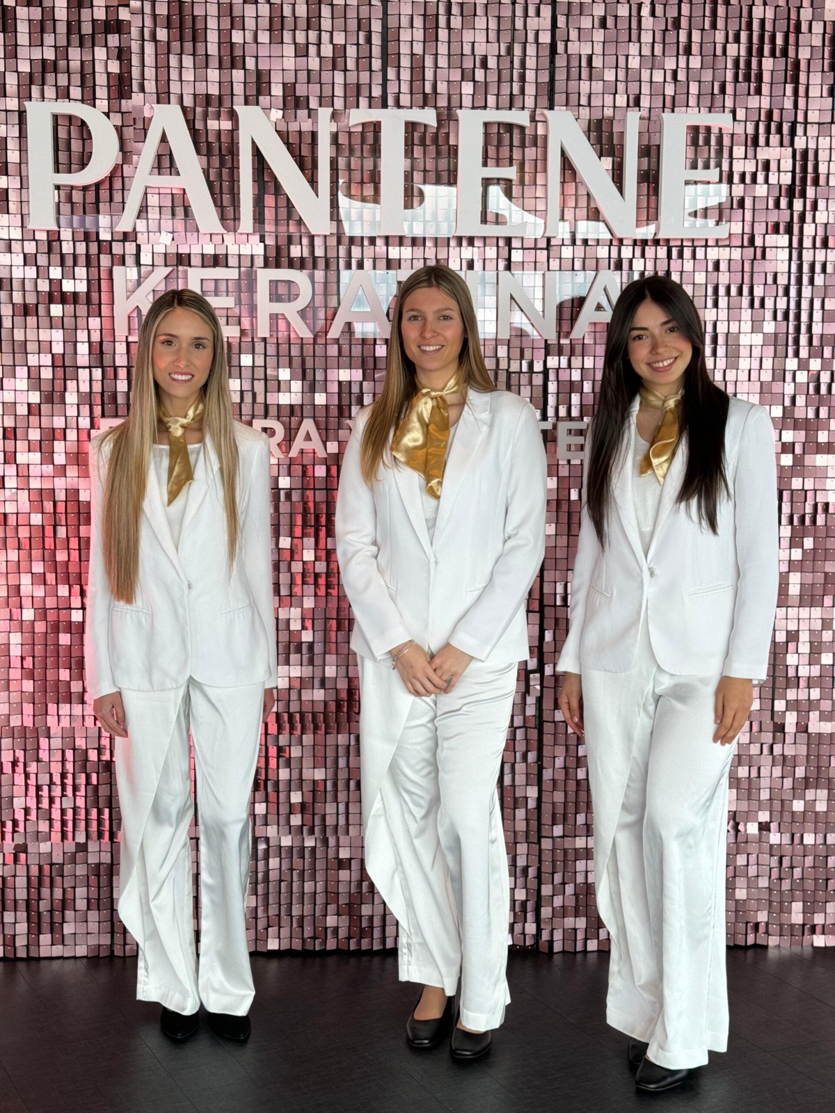 Promotoras de traje blanco frente a un fondo de lentejuelas rosas en el lanzamiento de Pantene Keratina.